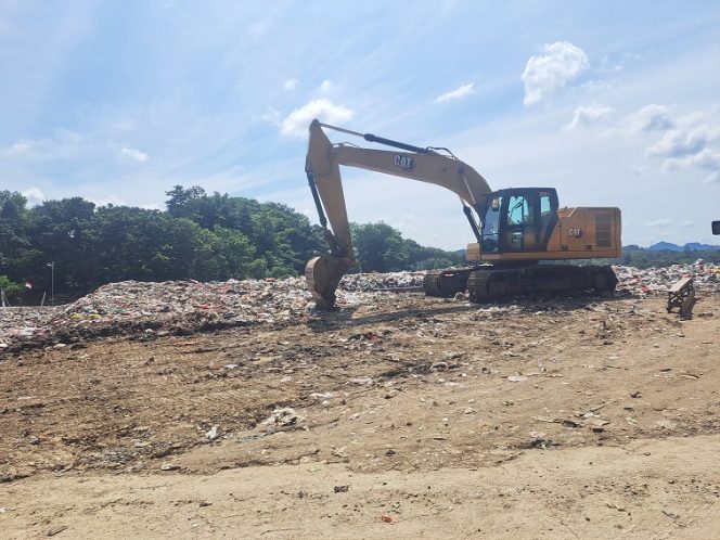 
Alat berat mengatur tumpukan sampah di TPA Bekotok, Kukar, yang kapasitasnya diperkirakan penuh pada 2029. (Angga/Okeborneo.com)