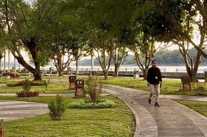 
Seorang warga melintas di ruang terbuka hijau kawasan tepi Sungai Mahakam, Tenggarong. (Angga/okeborneo.com)