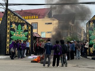 Sejumlah mahasiswa Unikarta menggelar aksi di depan Polres Kutai Kartanegara dengan membakar ban sebagai simbol protes, Selasa (24/2/2026). (Angga/Okeborneo.com)