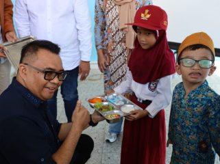 Bupati Kukar Aulia Rahman Basri menyerahkan makanan bergizi kepada siswa saat peresmian Dapur MBG SPPG Bintang Kaltim di Sangasanga. (okeborneo.com)