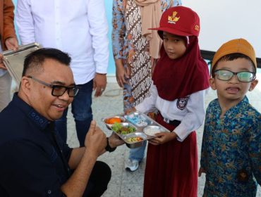 Bupati Kukar Aulia Rahman Basri menyerahkan makanan bergizi kepada siswa saat peresmian Dapur MBG SPPG Bintang Kaltim di Sangasanga. (okeborneo.com)