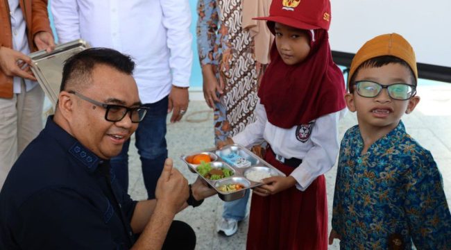 Bupati Kukar Aulia Rahman Basri menyerahkan makanan bergizi kepada siswa saat peresmian Dapur MBG SPPG Bintang Kaltim di Sangasanga. (okeborneo.com)
