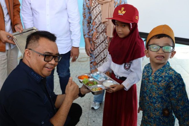 
Bupati Kukar Aulia Rahman Basri menyerahkan makanan bergizi kepada siswa saat peresmian Dapur MBG SPPG Bintang Kaltim di Sangasanga. (okeborneo.com)