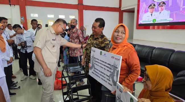 Bupati Kukar Aulia Rahman Basri menyerahkan bantuan sosial kepada veteran dan janda veteran dalam kegiatan penyaluran bantuan bagi kelompok rentan di BPU Tenggarong. (Istimewa)