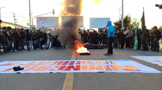 Massa Aliansi Gerakan Rakyat Menggugat Kaltim melakukan aksi teatrikal dengan membakar ban di simpang Jalan Slamet Riyadi, dekat Jembatan Mahakam, Samarinda, Kamis, 18 Juni 2026. Aksi tersebut turut mendesak DPRD Kaltim segera menindaklanjuti pembahasan hak angket. (Pep/OkeBorneo.com)
