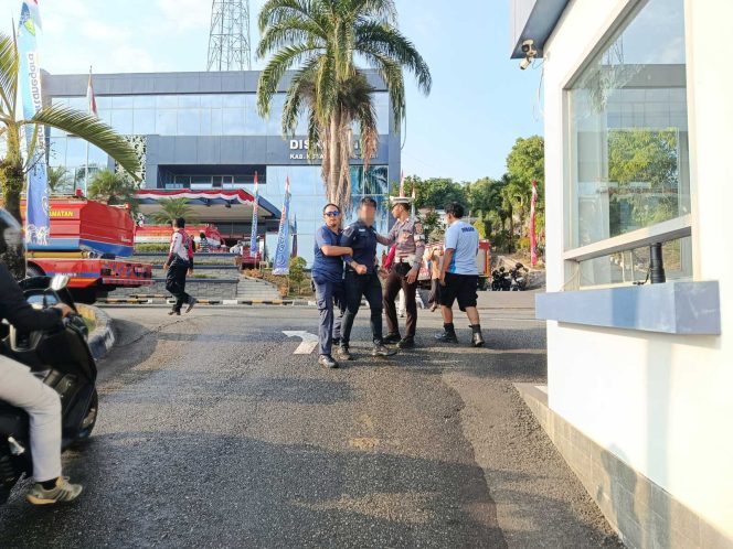 
Petugas mengamankan seorang pria di area Kantor Diskominfo Kukar setelah kebakaran melanda ruang rapat lantai tiga, Selasa (11/8/2026). (Istimewa)