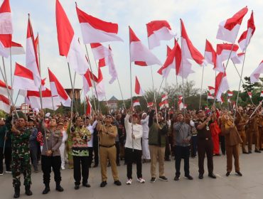 Bupati Kutai Kartanegara Aulia Rahman Basri bersama jajaran Forkopimda dan peserta mengibarkan bendera Merah Putih dalam Gerakan Nasional Pembagian dan Pemasangan Bendera Merah Putih di Tenggarong, Senin, 10 Agustus 2026. (angga/okeborneo.com)